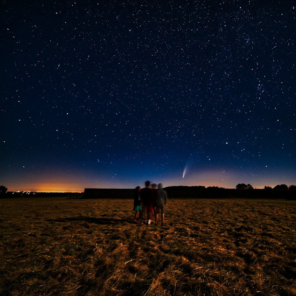 people standing on brown field under blue sky during night time