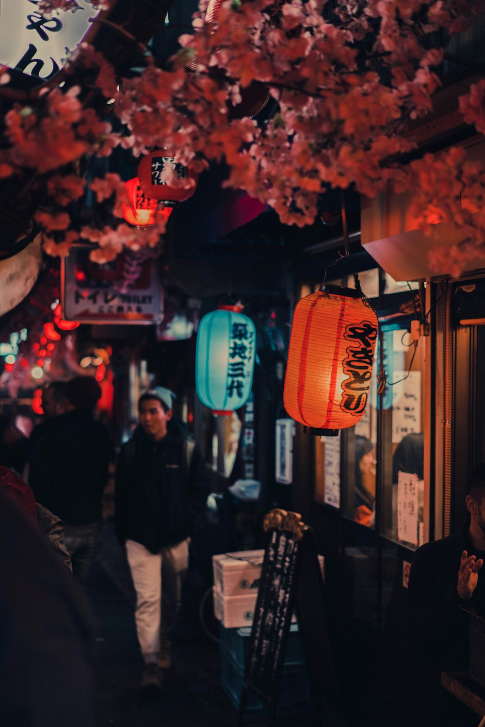 people standing near red paper lantern during nighttime