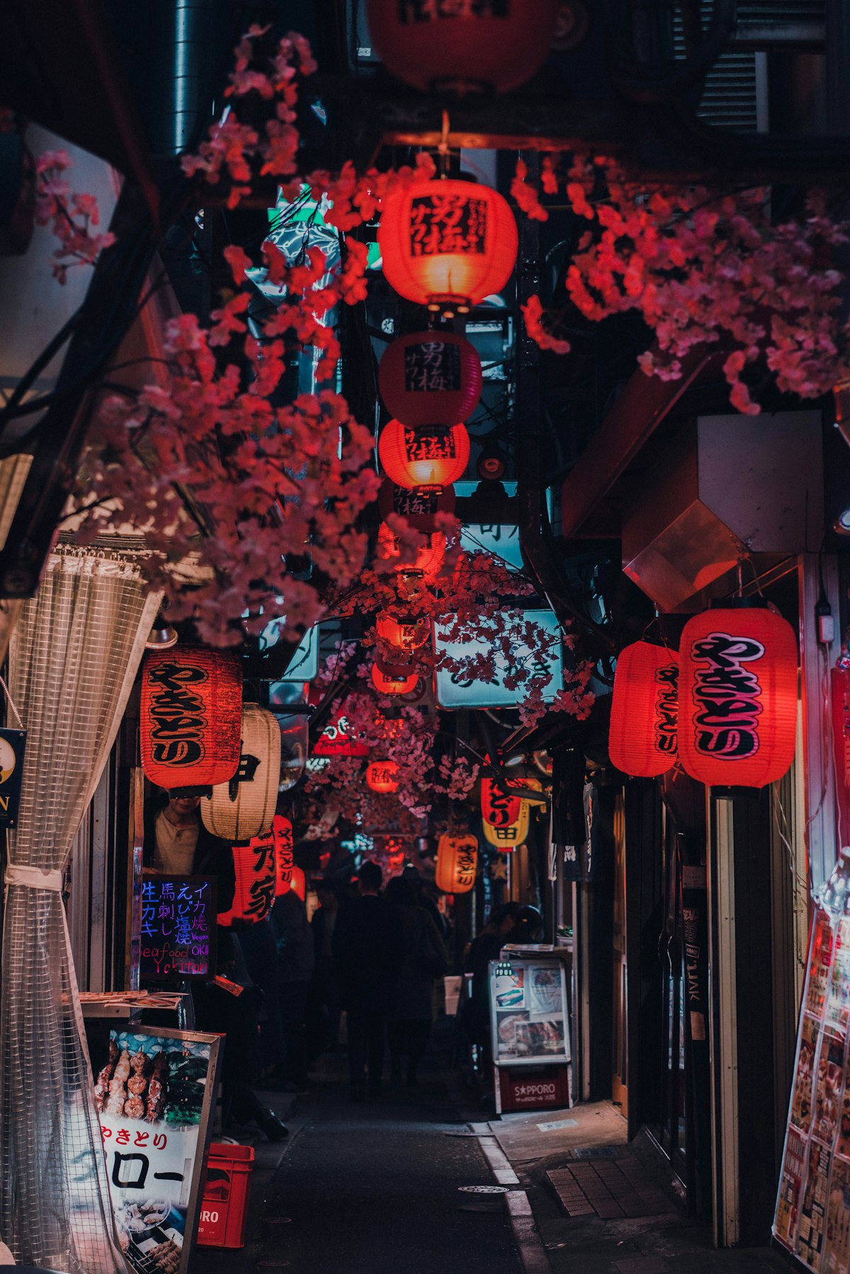 People walking a street lined with red lanterns in Shinjuku, Tokyo