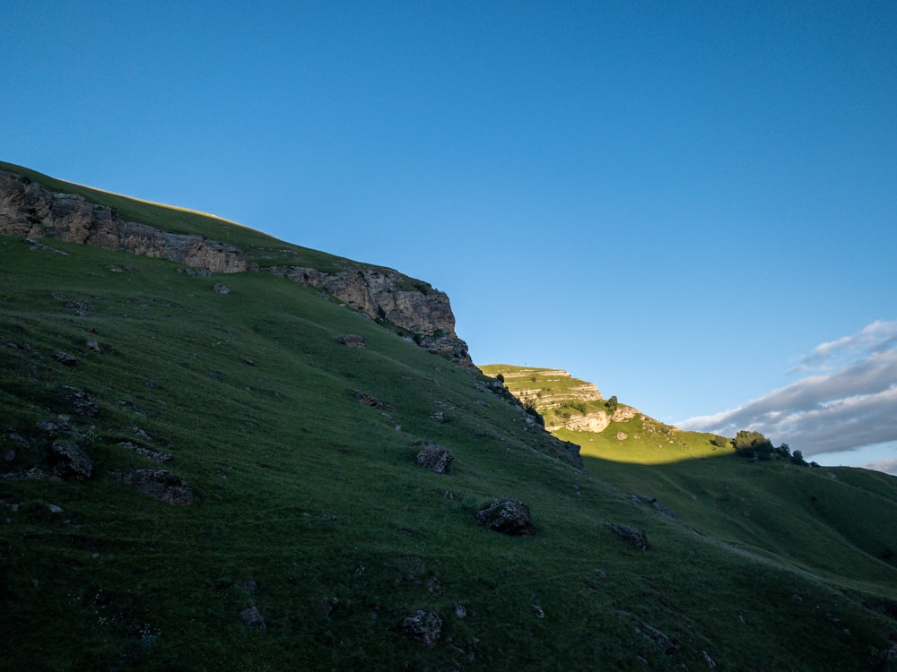 campo de hierba verde en la colina bajo el cielo azul durante el día