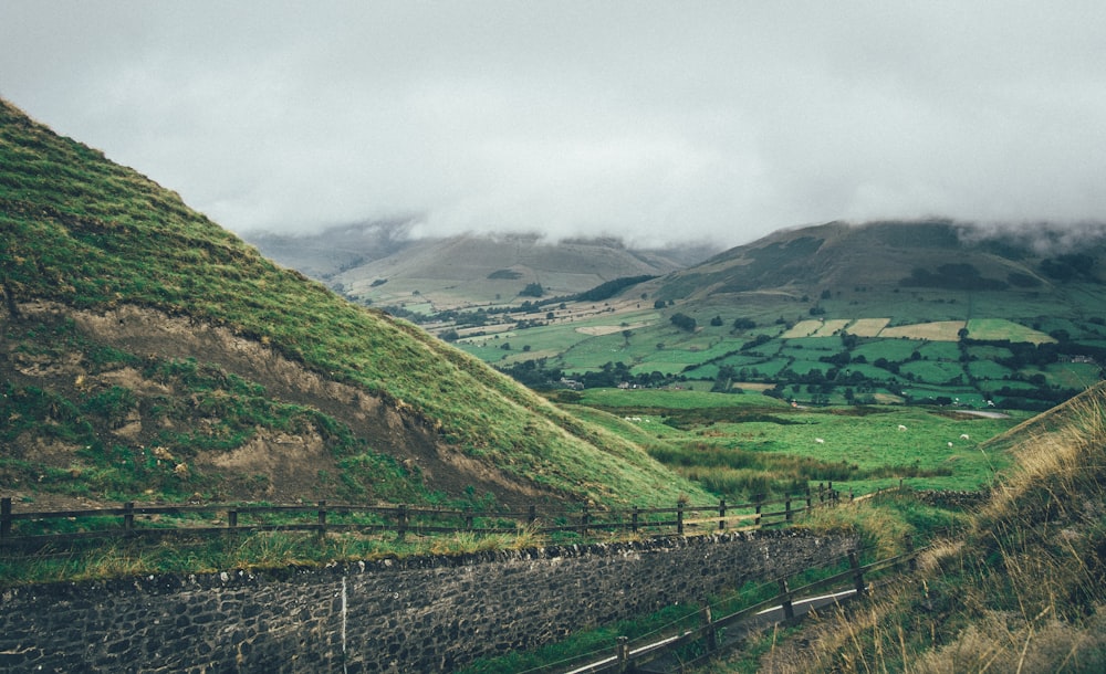 green grass field near mountain under white sky during daytime