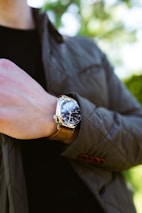 A casually dressed man adjusting his watch in a cozy urban setting.