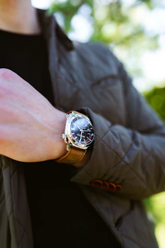 A stylish man adjusting his watch in warm natural light.
