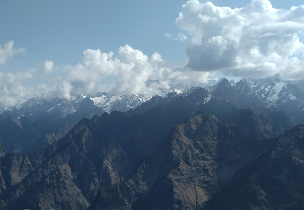 brown and black mountains under white clouds and blue sky during daytime