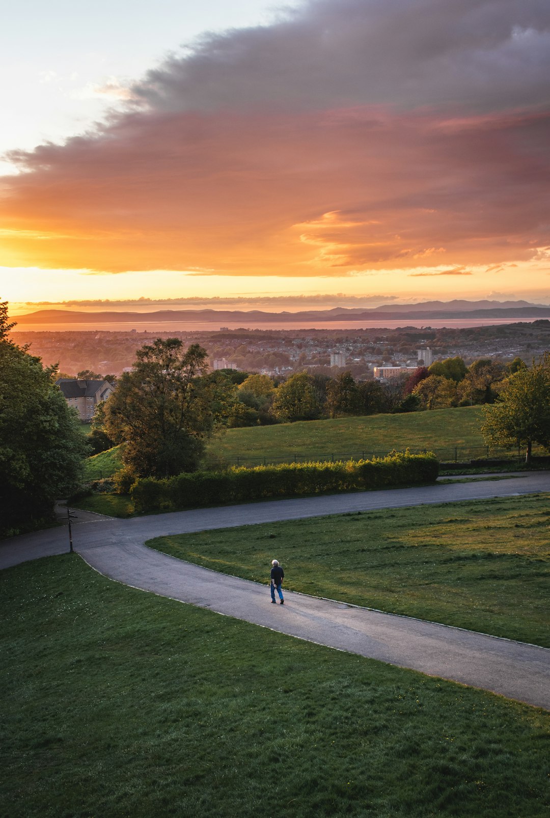 person in black shirt and black pants walking on gray concrete pathway during sunset