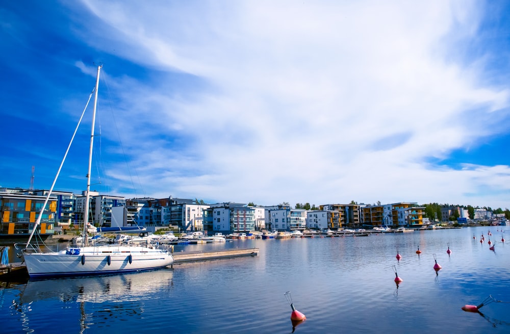 white and red boat on sea near city buildings under blue and white sunny cloudy sky