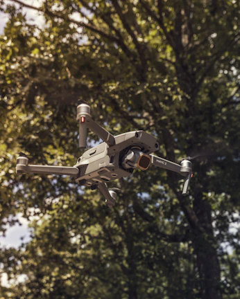 A sleek racing drone zooming through a narrow forest track at sunset.