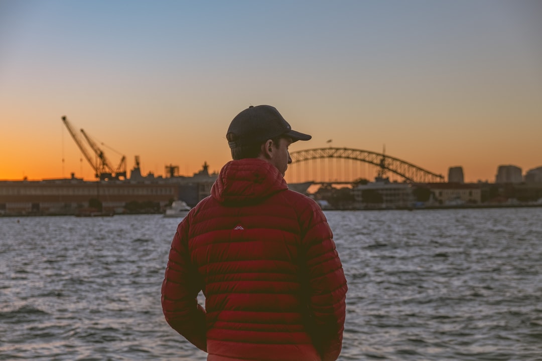 man in red hoodie standing near body of water during daytime