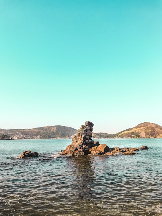 brown rock formation on blue sea under blue sky during daytime in Niterói Brasil