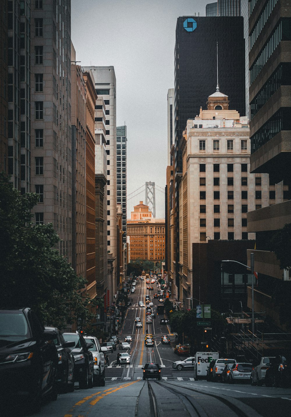 cars on road in between high rise buildings during daytime