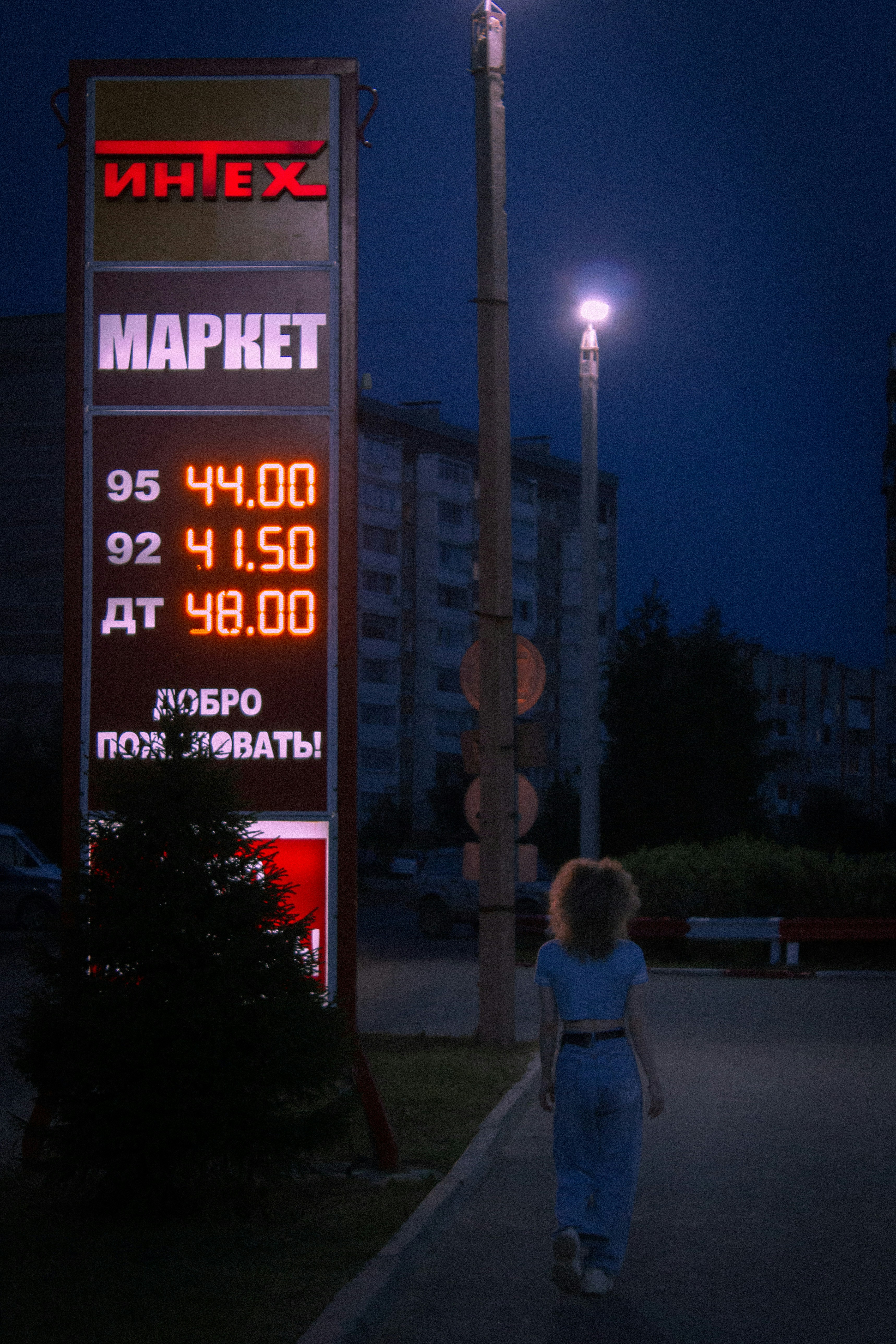 girl in white jacket standing near the building during night time