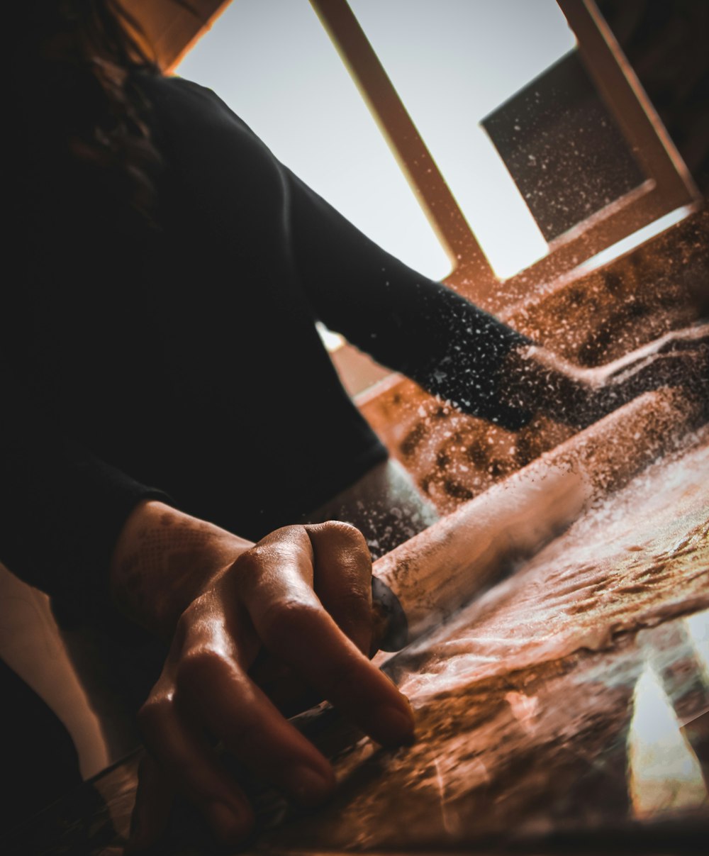 person in black long sleeve shirt holding brown wooden table