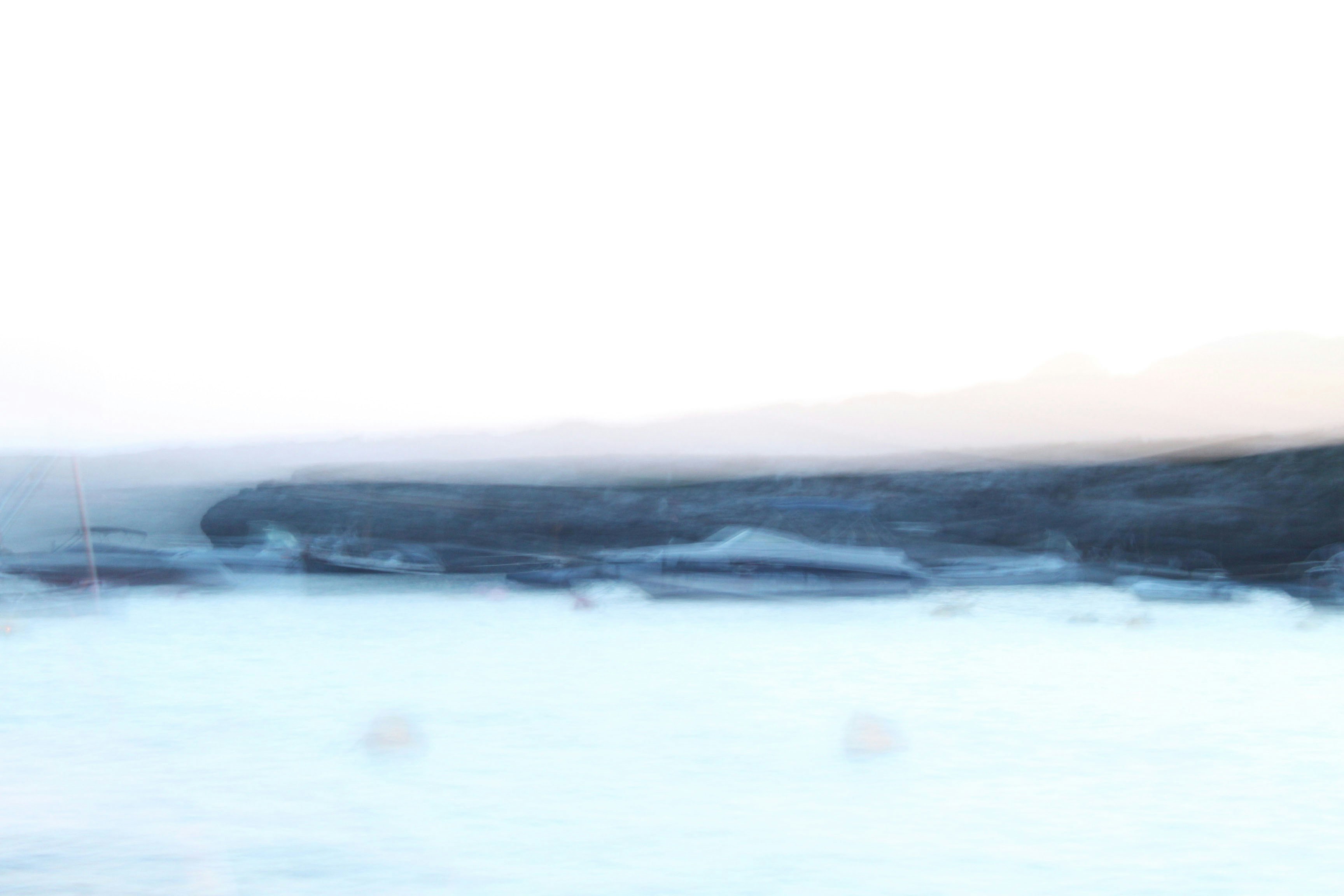 A ghostly image of the ocean from which a coastline is barely visible. 