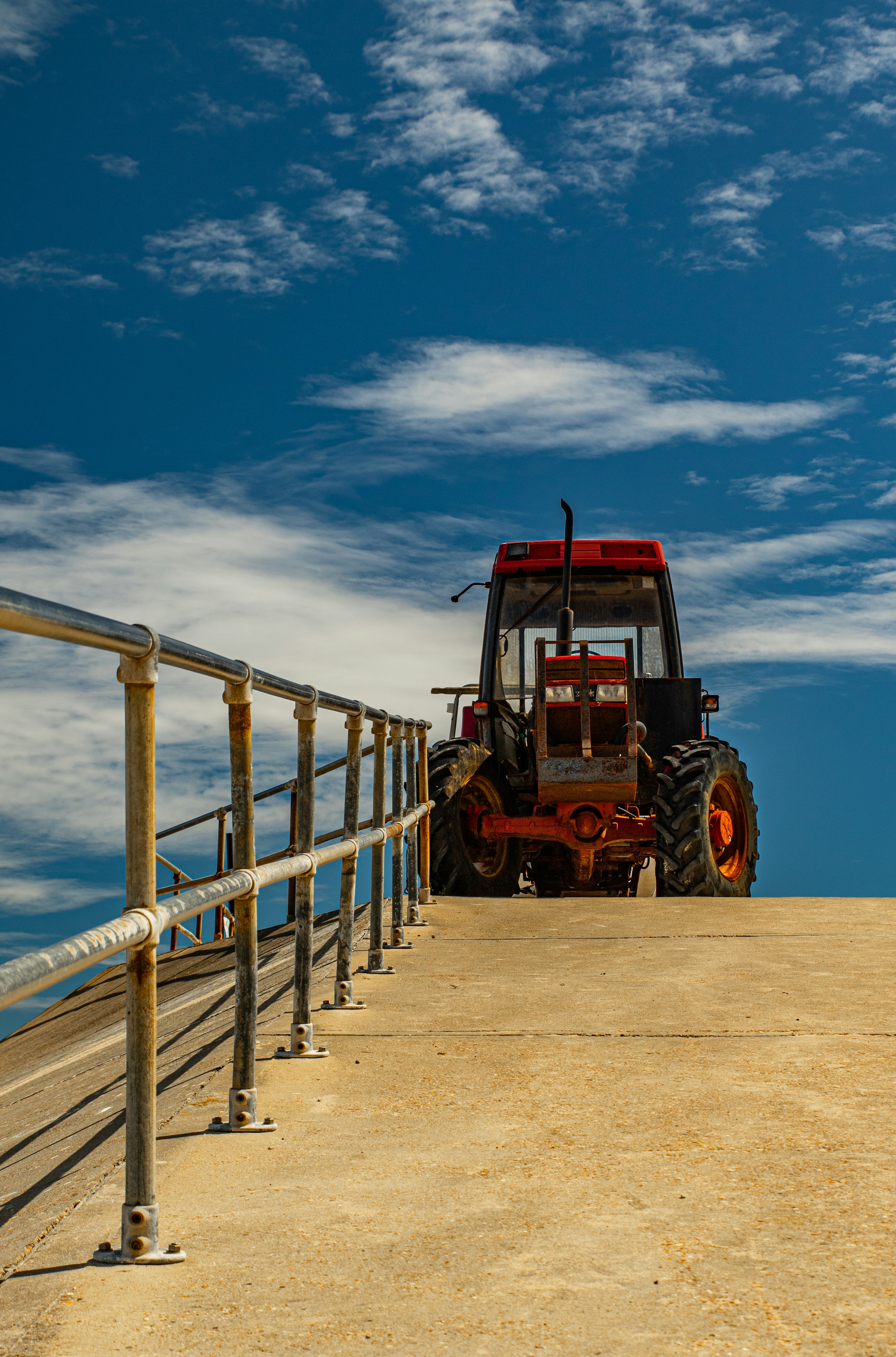 red tractor on brown sand near body of water during daytime