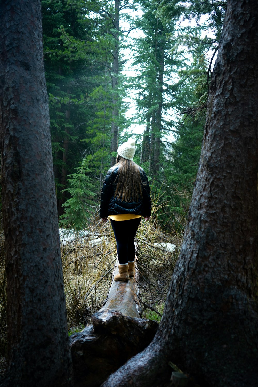 woman in black shirt and white shorts standing in the middle of the forest during daytime