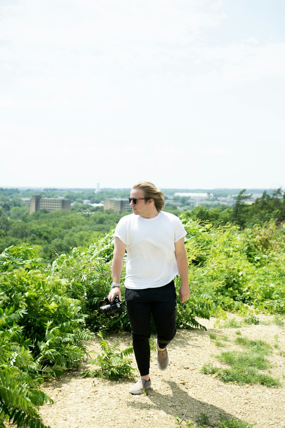 man in white crew neck t-shirt and black pants standing on green grass field during