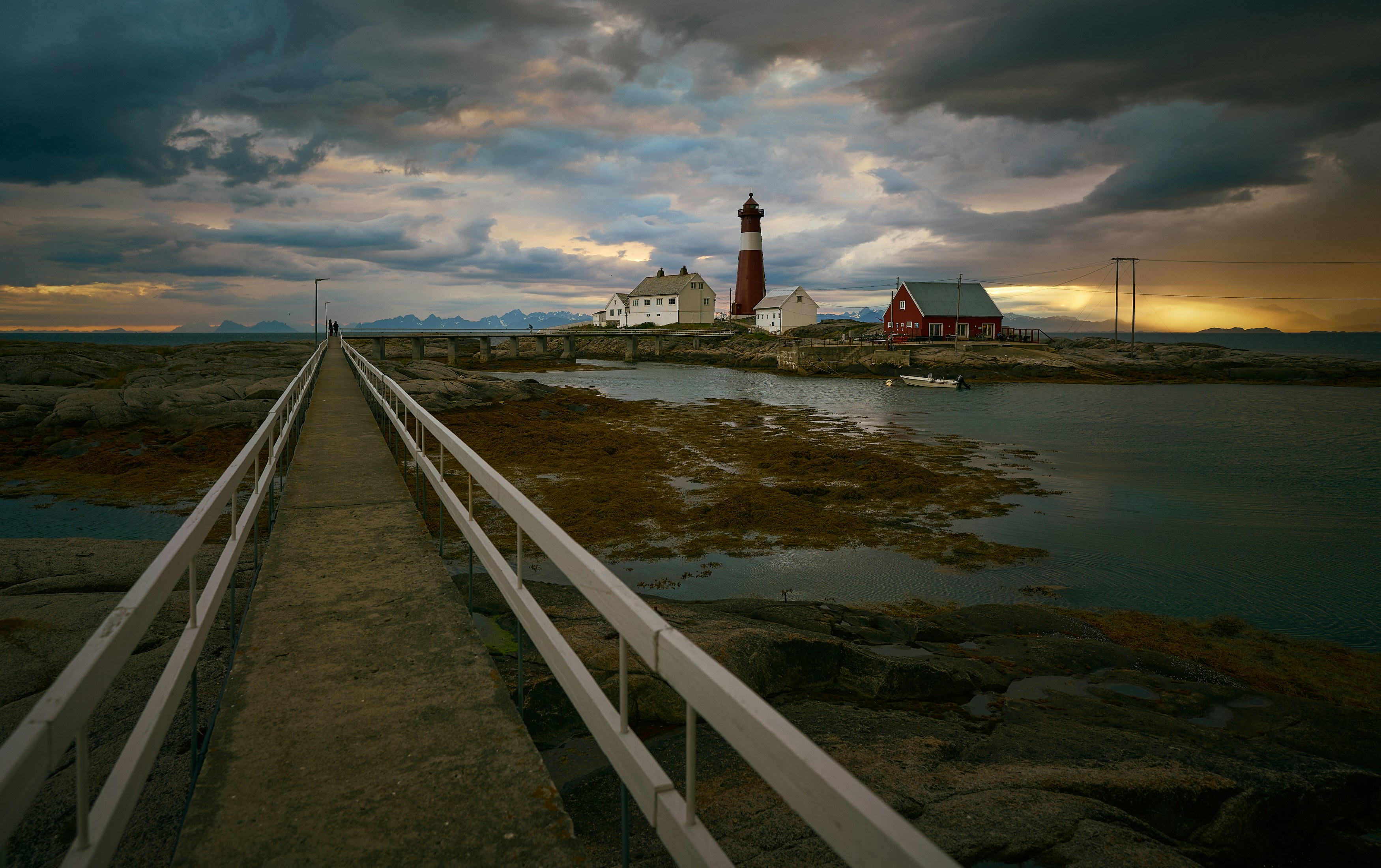 White and red lighthouse near body of water under cloudy sky during ...
