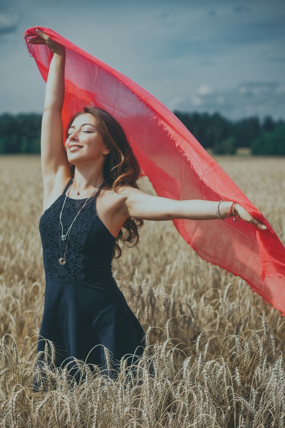 woman in black spaghetti strap dress holding red umbrella