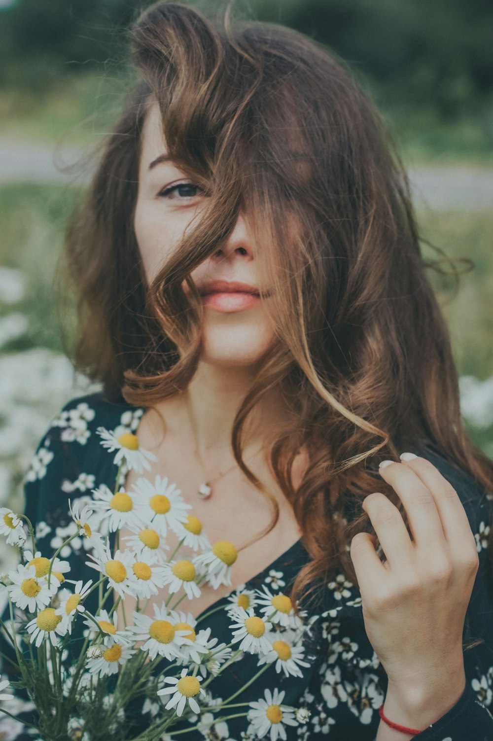 woman in black and yellow floral shirt holding her hair