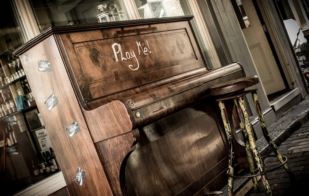 brown wooden upright piano with chair