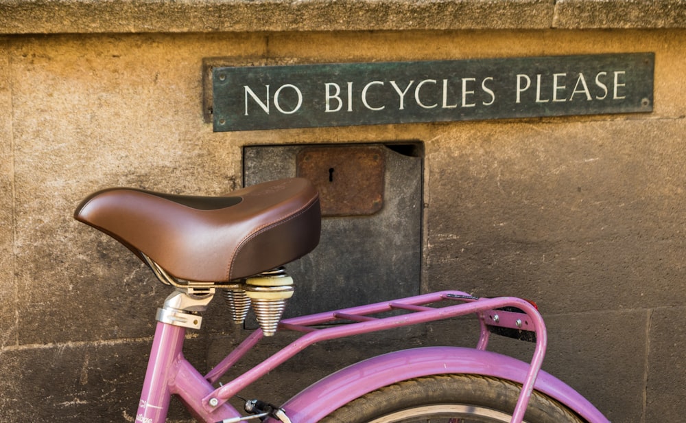 pink bicycle parked beside brown concrete wall