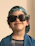 Smiling toddler wearing a colorful hat and sunglasses from Pantalones Chic outdoors.