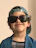 Smiling toddler wearing a colorful hat and sunglasses from Pantalones Chic outdoors.