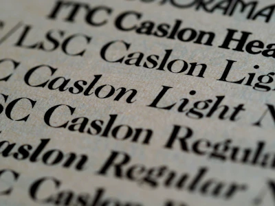 Close-up of hands carefully selecting typefaces on a charcoal gray palette with dusty rose swatches nearby.