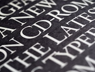A close-up view of text on a dark background, featuring large, bold, white typography. The text appears to be printed on a textured surface, with words such as 'CD-ROM' clearly visible.
