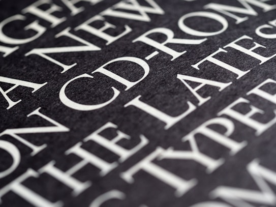 A close-up view of text on a dark background, featuring large, bold, white typography. The text appears to be printed on a textured surface, with words such as 'CD-ROM' clearly visible.