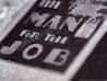 Close-up of text reading 'The Man For The Job' in bold, prominent letters on a textured surface, suggesting a vintage or classic style.