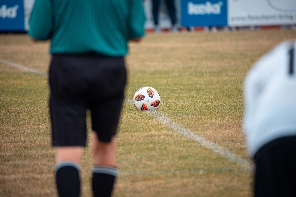 Mann in grünem Hemd und schwarzen Shorts beim Fußballspielen tagsüber