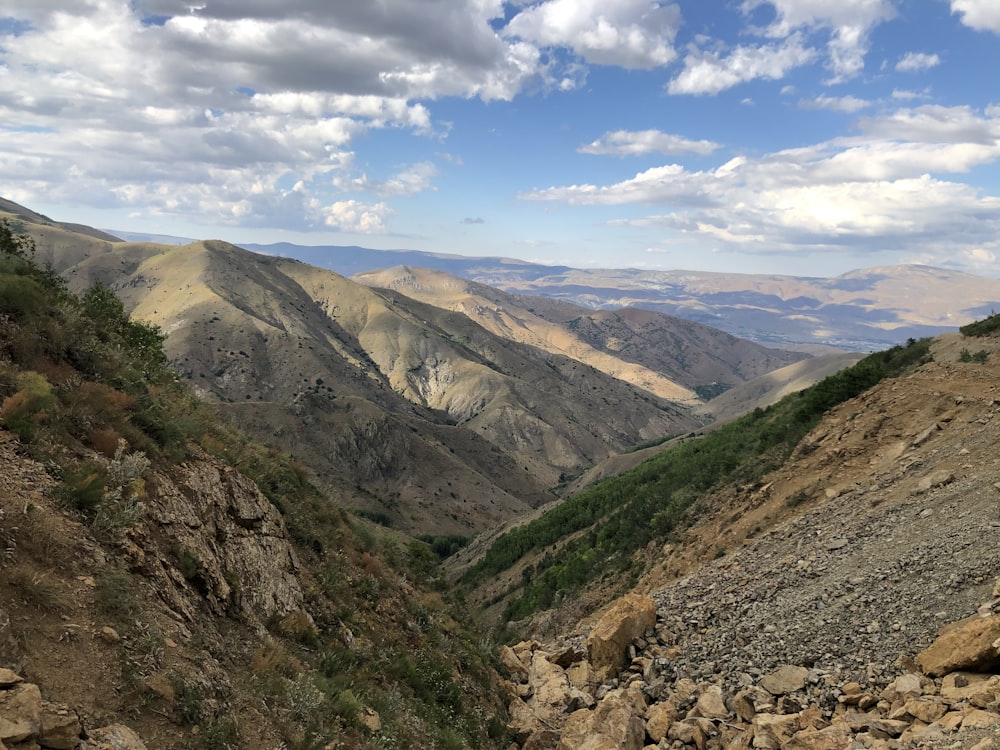 brown and green mountains under white clouds and blue sky during daytime