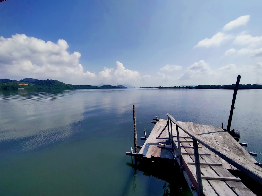brown wooden dock on body of water under blue sky during daytime
