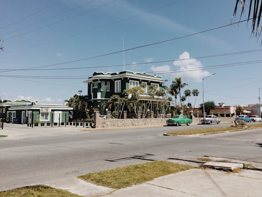 white and green concrete building near green trees during daytime in Cienfuegos Cuba