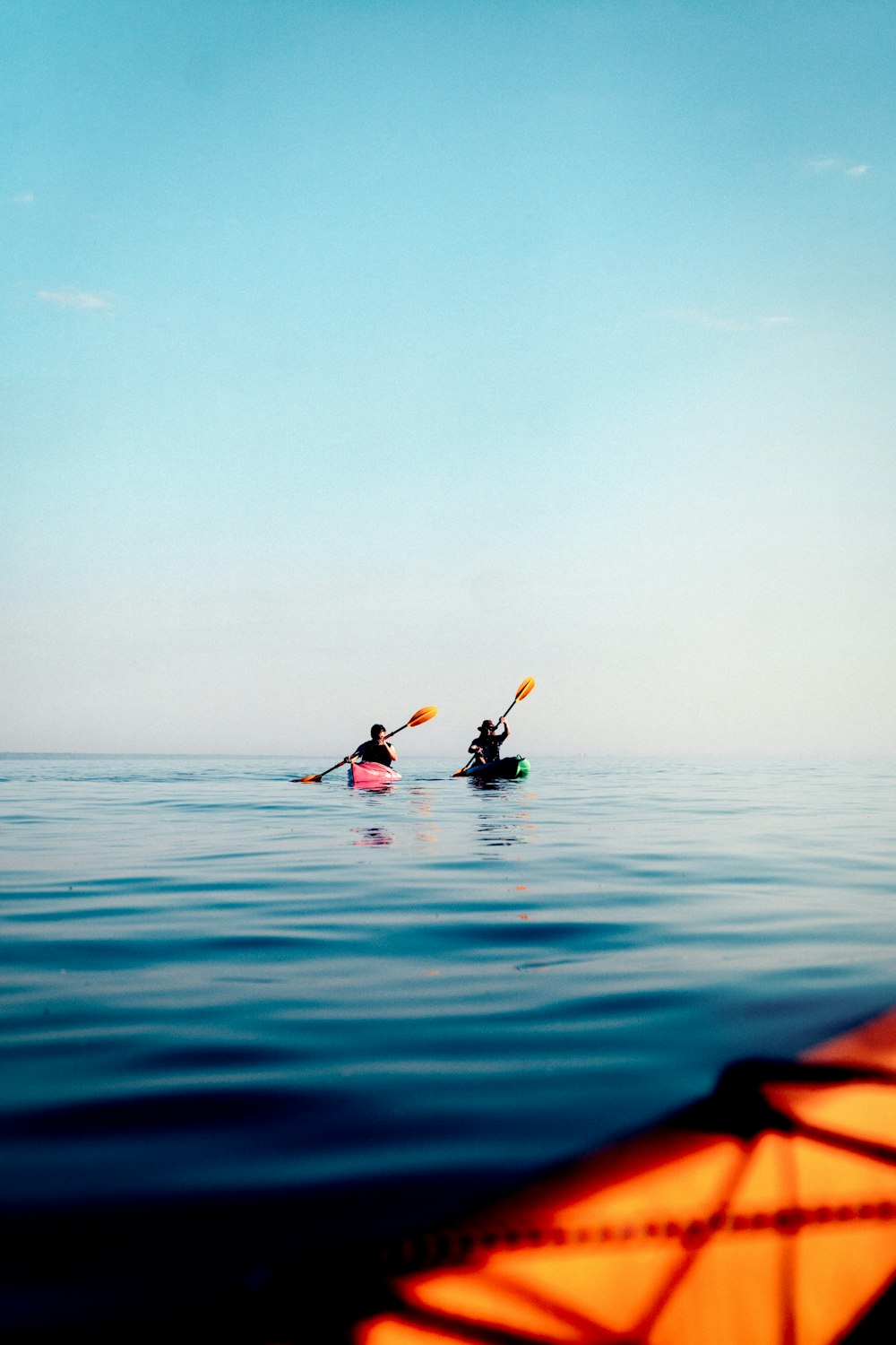 Person im schwarzen Neoprenanzug, die tagsüber auf dem blauen Meer Kajak fährt