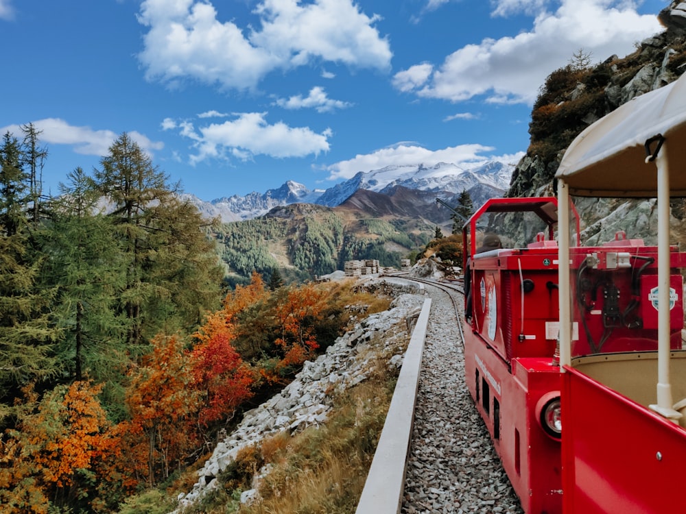 red train on rail road near trees and mountains during daytime