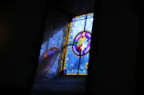 Finished stained glass artwork hanging by a window, casting vibrant reflections.