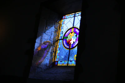 Finished stained glass artwork hanging by a window, casting vibrant reflections.