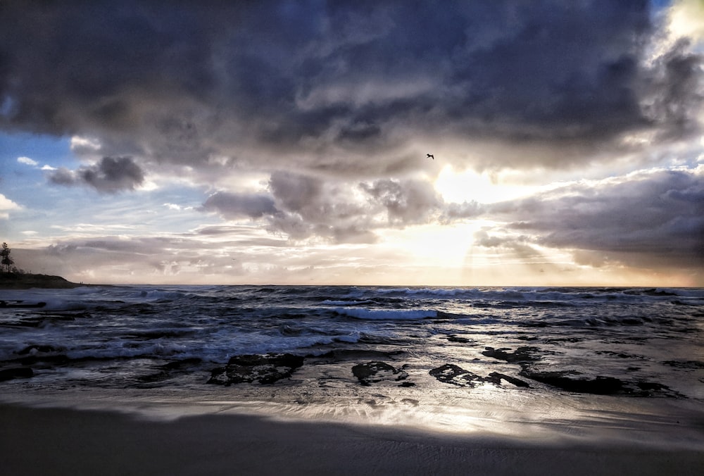 ocean waves crashing on shore during sunset