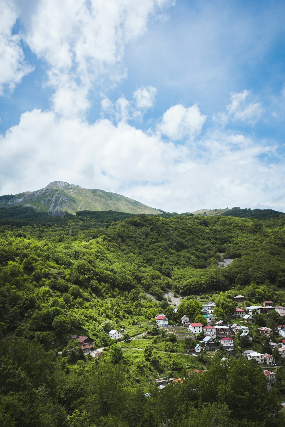 montaña verde bajo nubes blancas durante el día