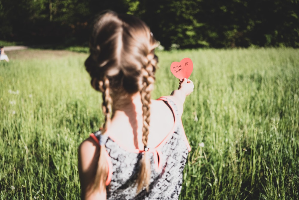 woman in white and black floral tank top holding heart balloon