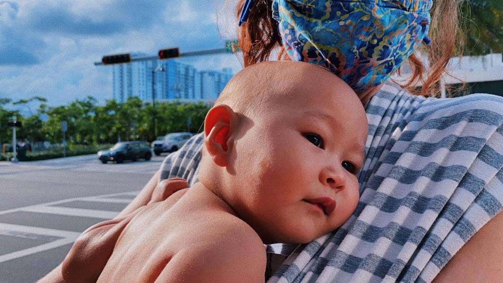 woman in blue and white shirt carrying baby in white and black stripe shirt