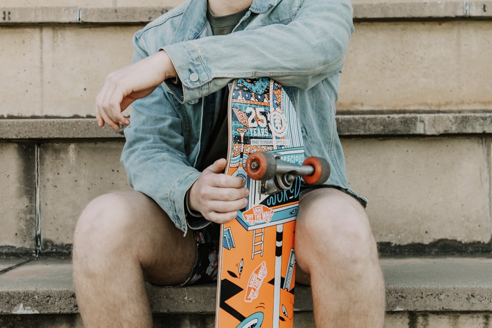 woman in gray long sleeve shirt holding blue and red skateboard