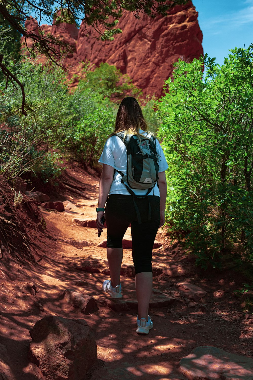 woman in blue t-shirt and black shorts walking on dirt road during daytime