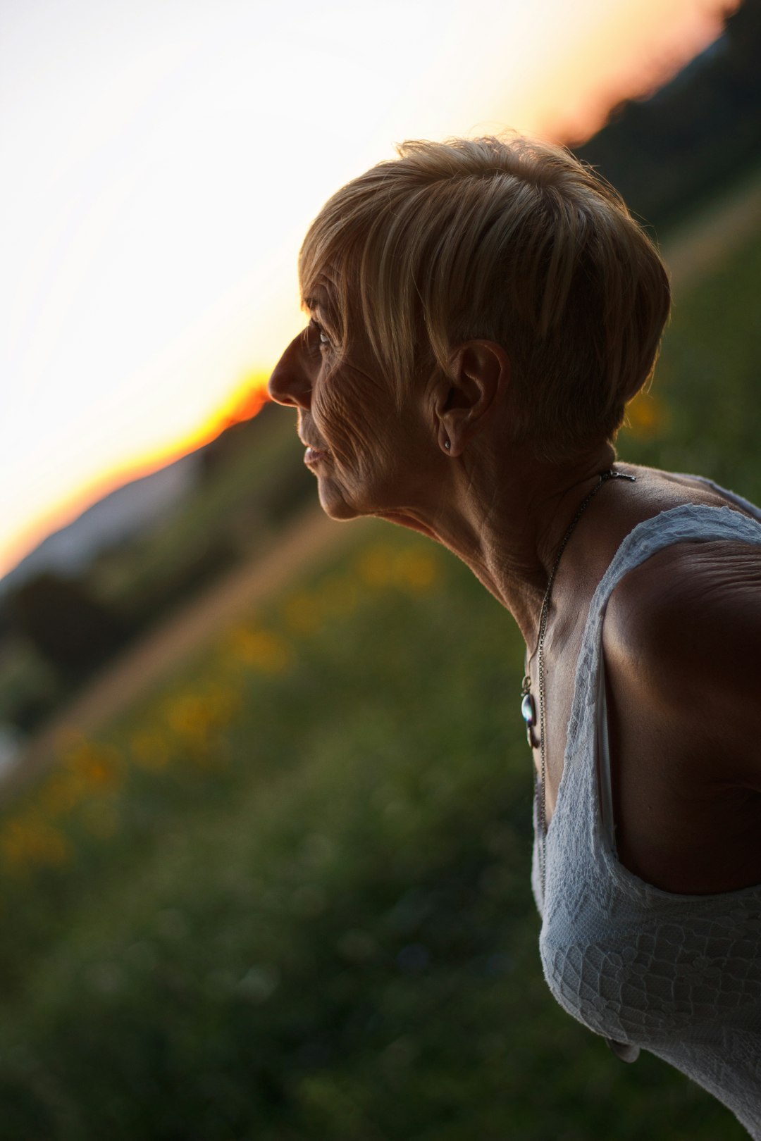 woman in white tank top standing on green grass field during daytime