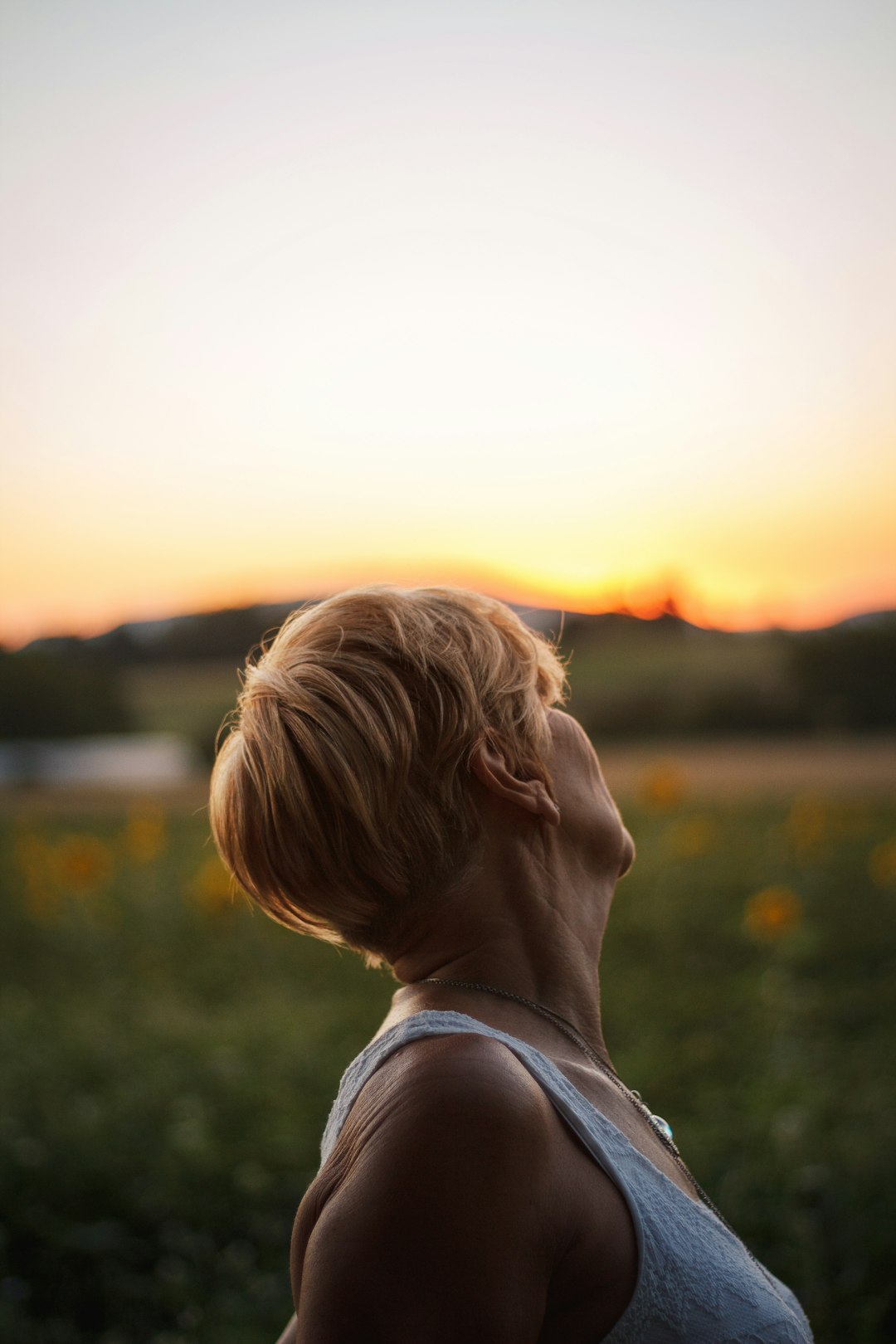 girl in white tank top looking at the sunset