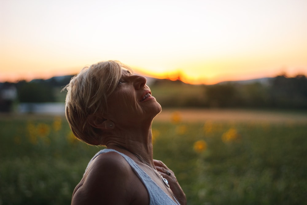 woman in white tank top looking at the sunset