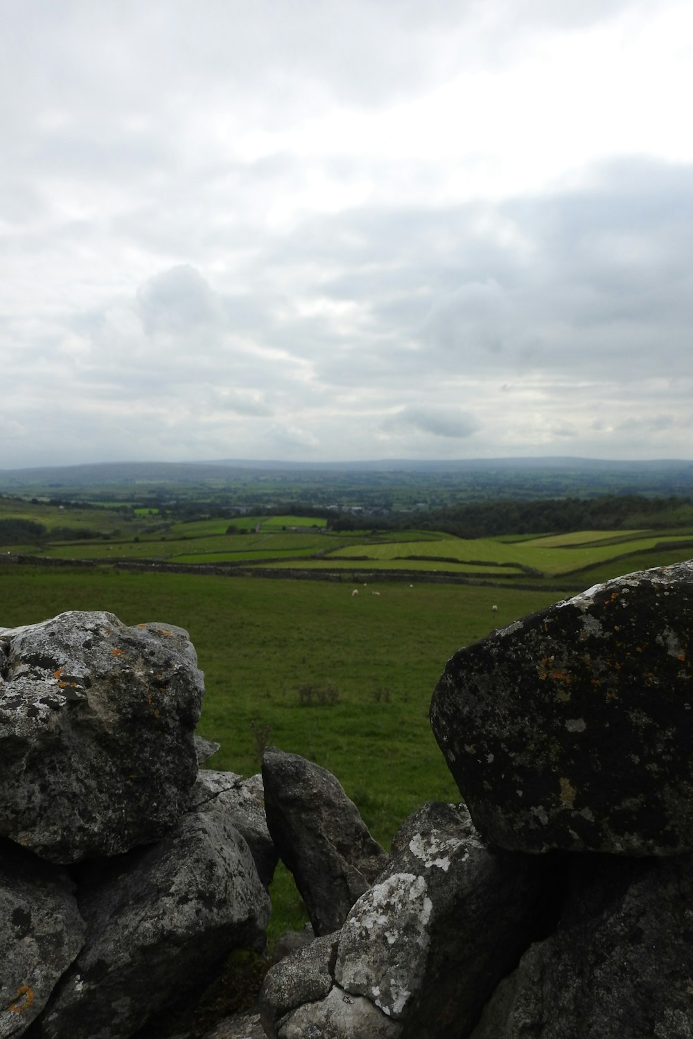 gray rock on green grass field under white clouds during daytime