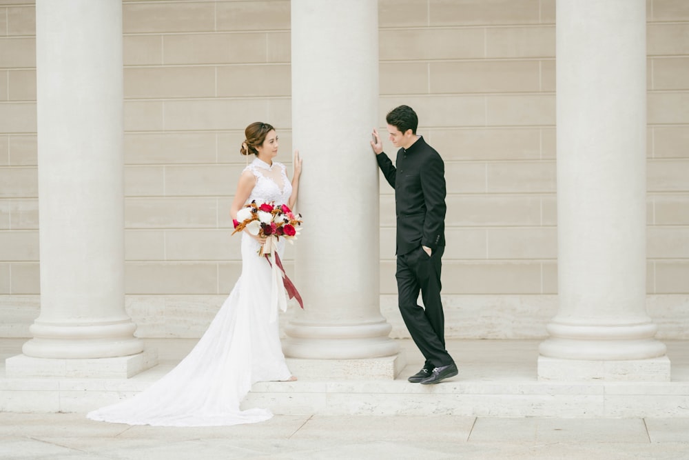 homme en costume noir et femme en robe de mariée blanche s’embrassant